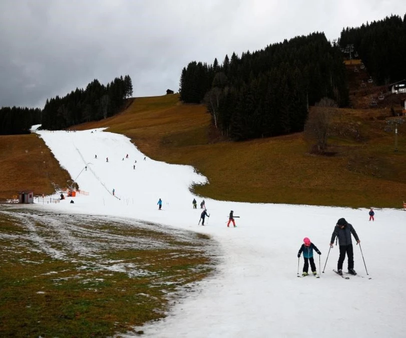 Skiers pass on a small layer of an artificial snow slope between grassland amid warmer-than-usual winter temperatures in the Alps in Filzmoos, Austria, January 5, 2023. REUTERSPIX Skiers pass on a small layer of an artificial snow slope between grassland amid warmer-than-usual winter temperatures in the Alps in Filzmoos, Austria, January 5, 2023. REUTERSPIX