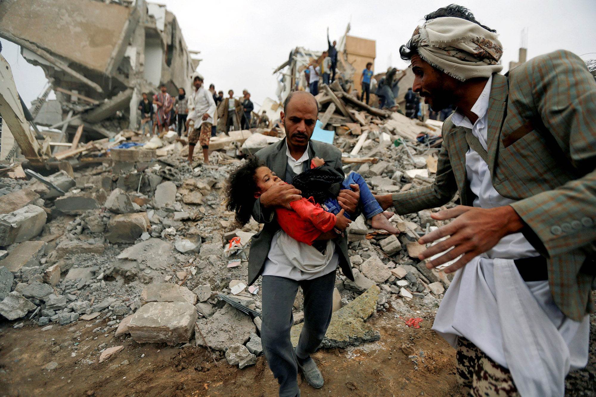 A man carries Buthaina Mohammed Mansour, believed to be 4 or 5, rescued from a site targetted by an airstrike that killed eight of her family members in Sana'a, Yemen | Reuters