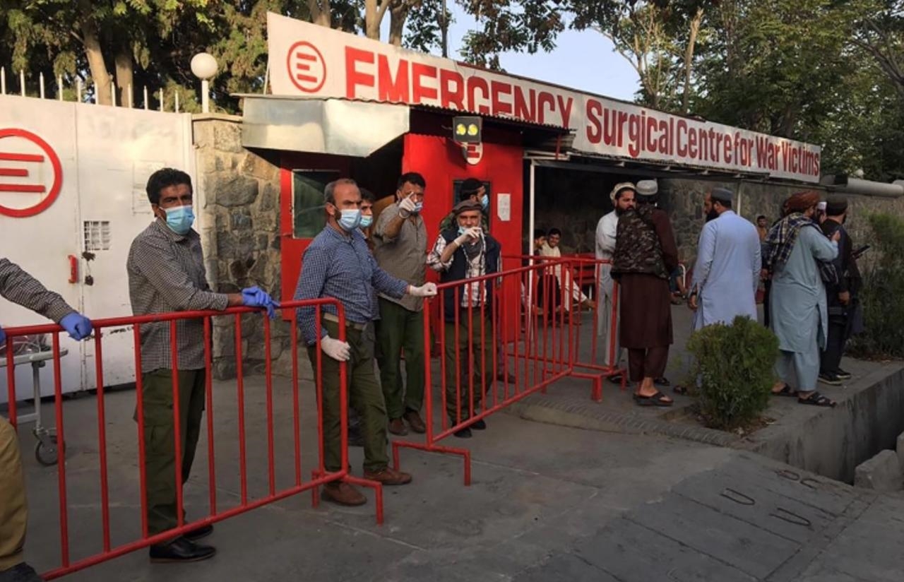 Medics stand at the entrance of a hospital as they wait to receive victims of an explosion in Kabul on October 3, 2021