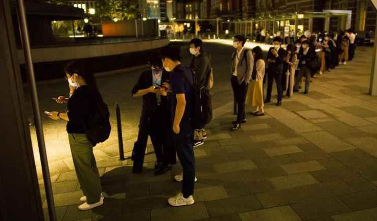 People waiting in line outside the Tokyo station as earthquake suspends the train services