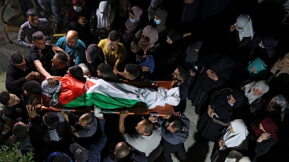 Mourners carry the body of Mohammed Khabisa, a Palestinian who was shot dead by Israeli troops, during his funeral in the occupied West Bank village of Beita, on September 24, 2021 | AFP