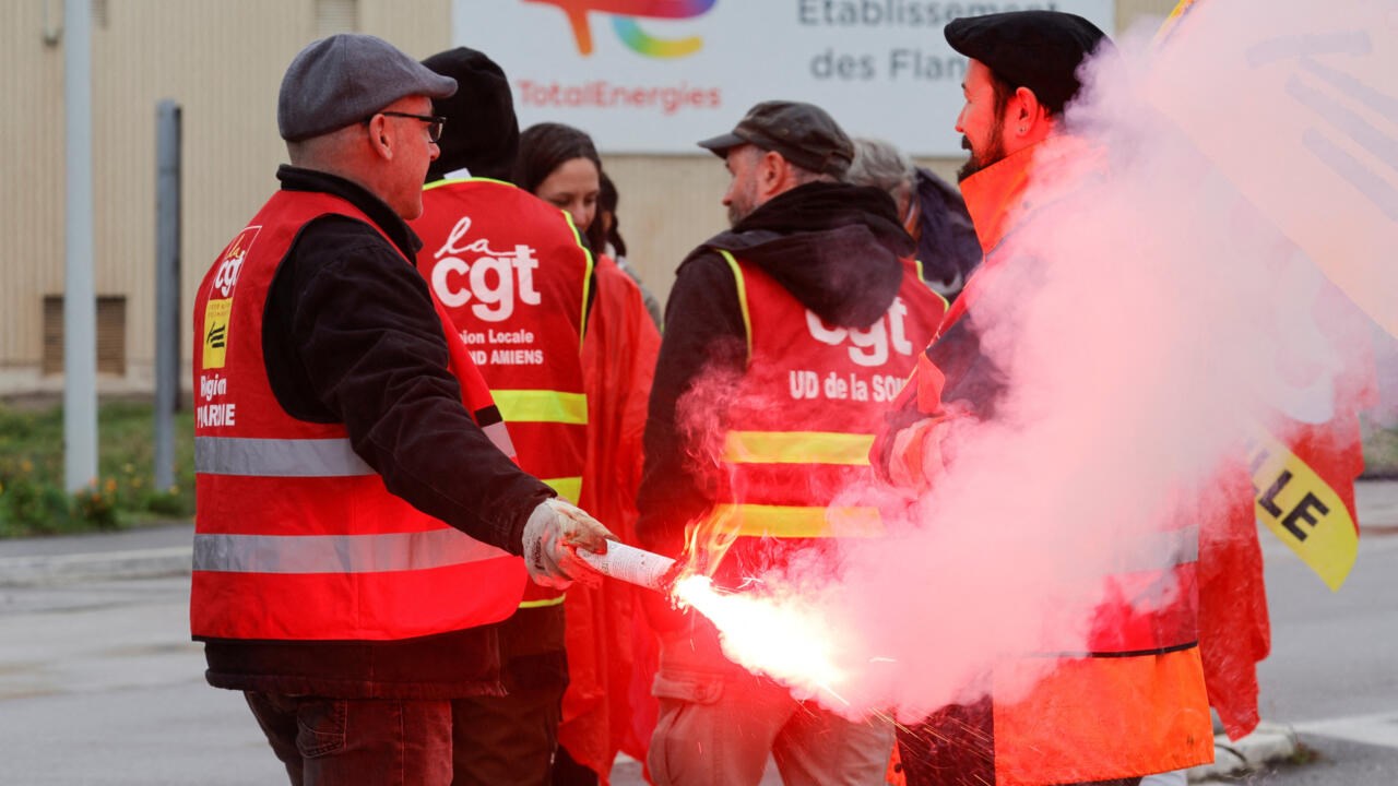 Striking workers use a red flare in front of Total gasoline tanks, October 13, 2022 (Reuters)