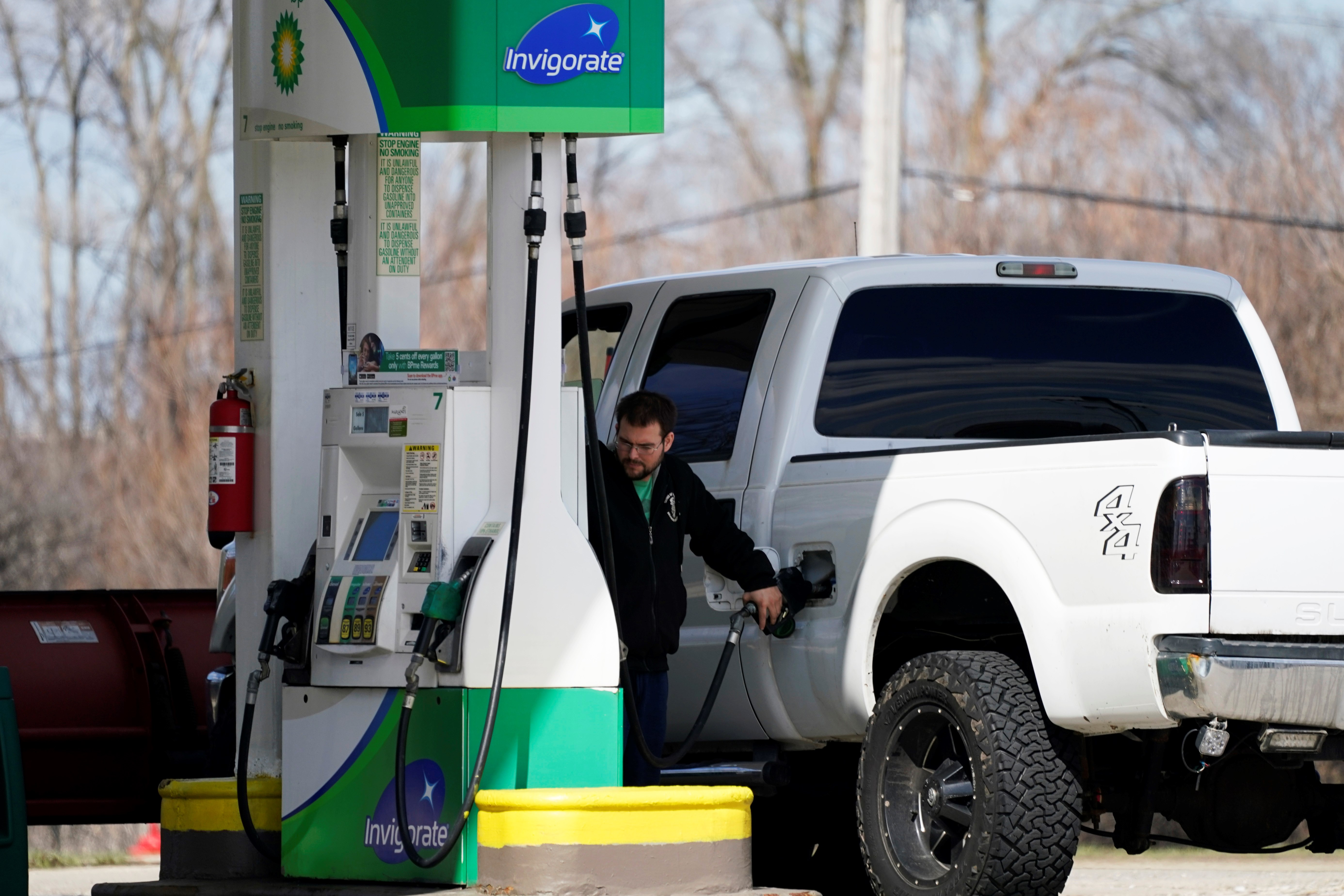 A man fills up his gas tank as he checks gas price at a gas station in Rolling Meadows, Ill., US, Friday, April 1, 2022 (AP Photo/Nam Y. Huh)
