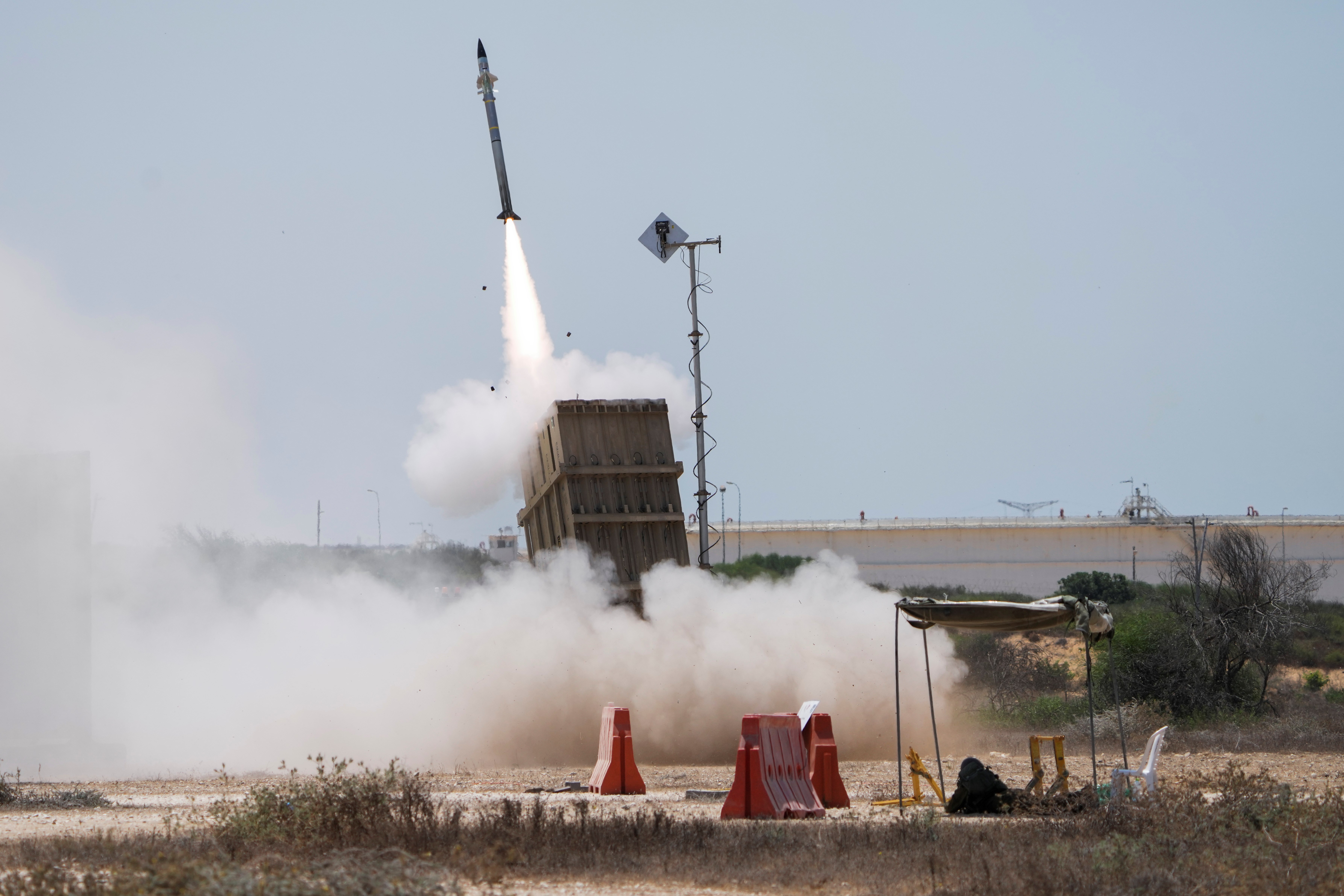 An Israeli soldier takes cover as an Iron Dome air system launches, Sunday, Aug. 7, 2022 (AP Photo/Ariel Schalit)