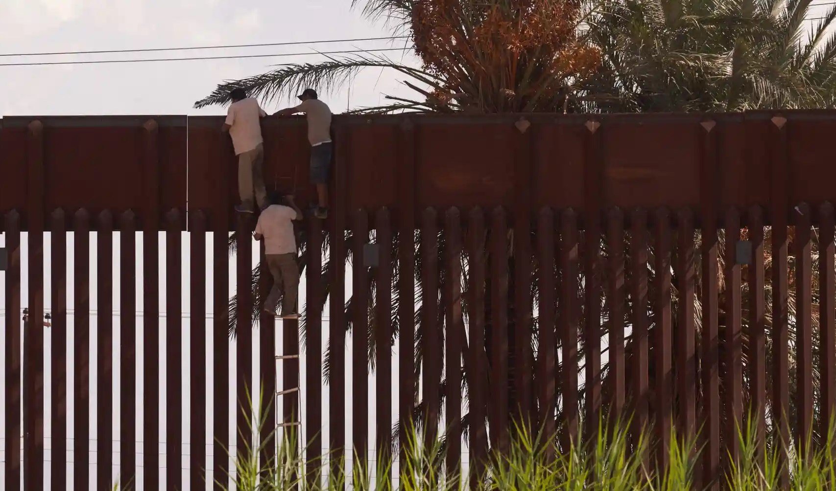 Migrants use a rope ladder to illegally climb over the US-Mexico border wall in El Centro, California. Photograph: Allison Dinner/AFP/Getty Images