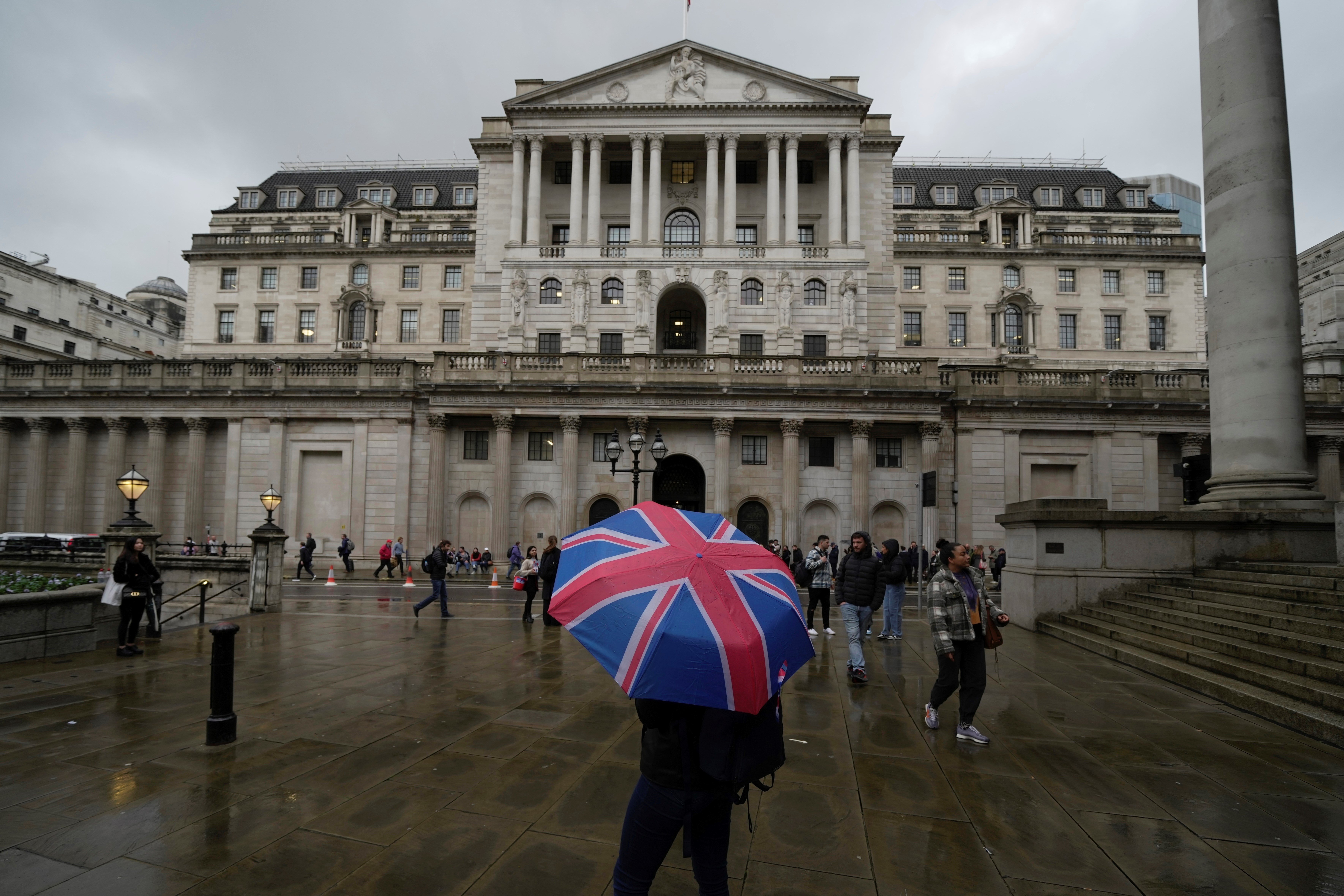 A woman with an umbrella stands in front of the Bank of England, at the financial district in London, Thursday, Nov. 3, 2022 (AP Photo/Kin Cheung)
