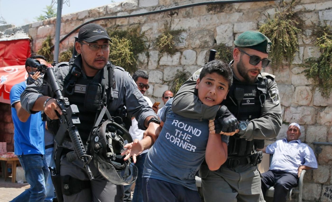 The IOF detaining a Palestinian child (AFP)