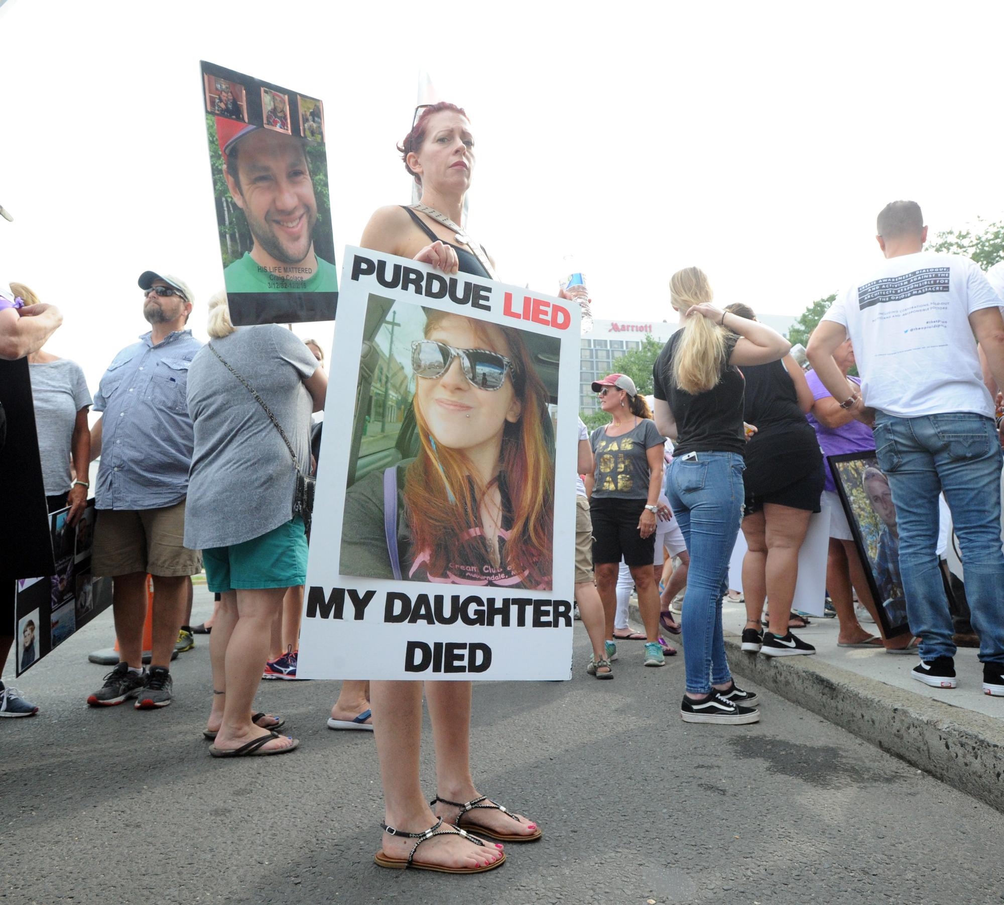 A protestor holds a picture of her dead daughter, who had used OxyContin