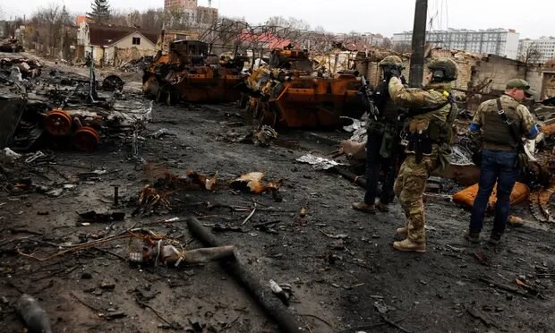 A Ukrainian soldier photographs a destroyed Russian tank and armoured vehicle in Bucha near Kyiv, scene of alleged war crimes. Photograph: Zohra Bensemra/Reuters