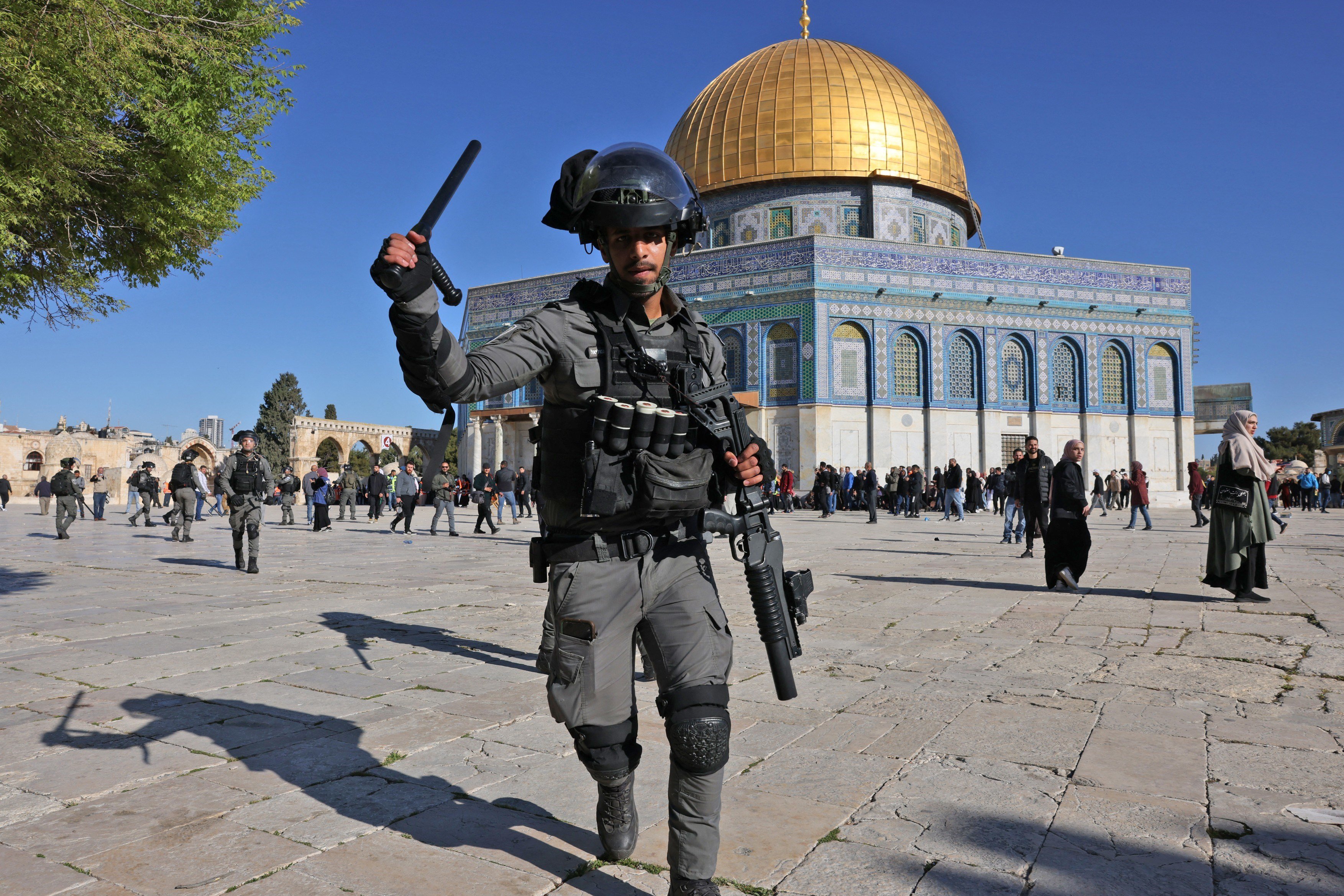 A member of the Israeli occupation forces attacks worshippers in Al-Aqsa mosque compound, on 15 April 2022 (AFP)