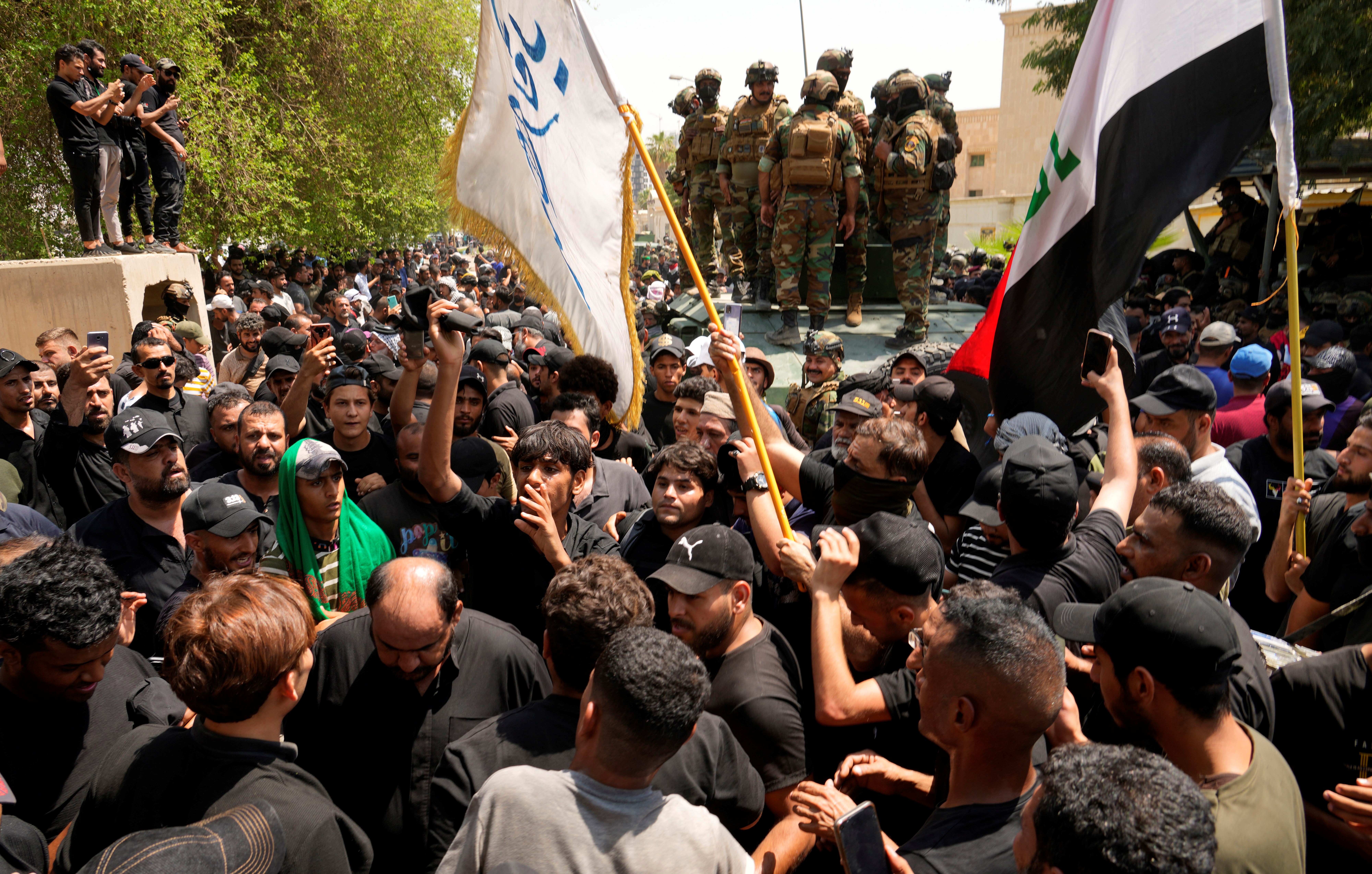 Supporters of Muqtada al-Sadr surround a vehicle with soldiers during a protest in front the Supreme Judicial Council, in Baghdad, Iraq, Tuesday, Aug. 23, 2022 (AP Photo/Hadi Mizban)