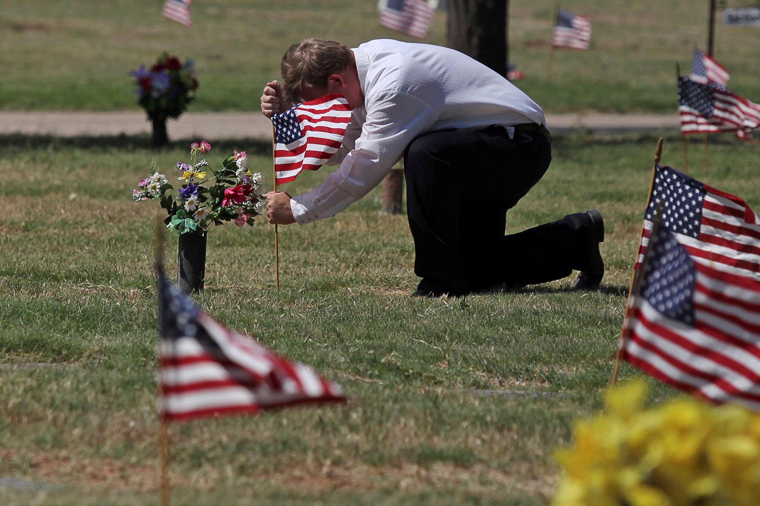 James Kohr places an American flag at a veteran's grave at Sunset Memorial Gardens in Odessa, Texas, on May 28.Jacob Ford / Odessa American via AP file.
