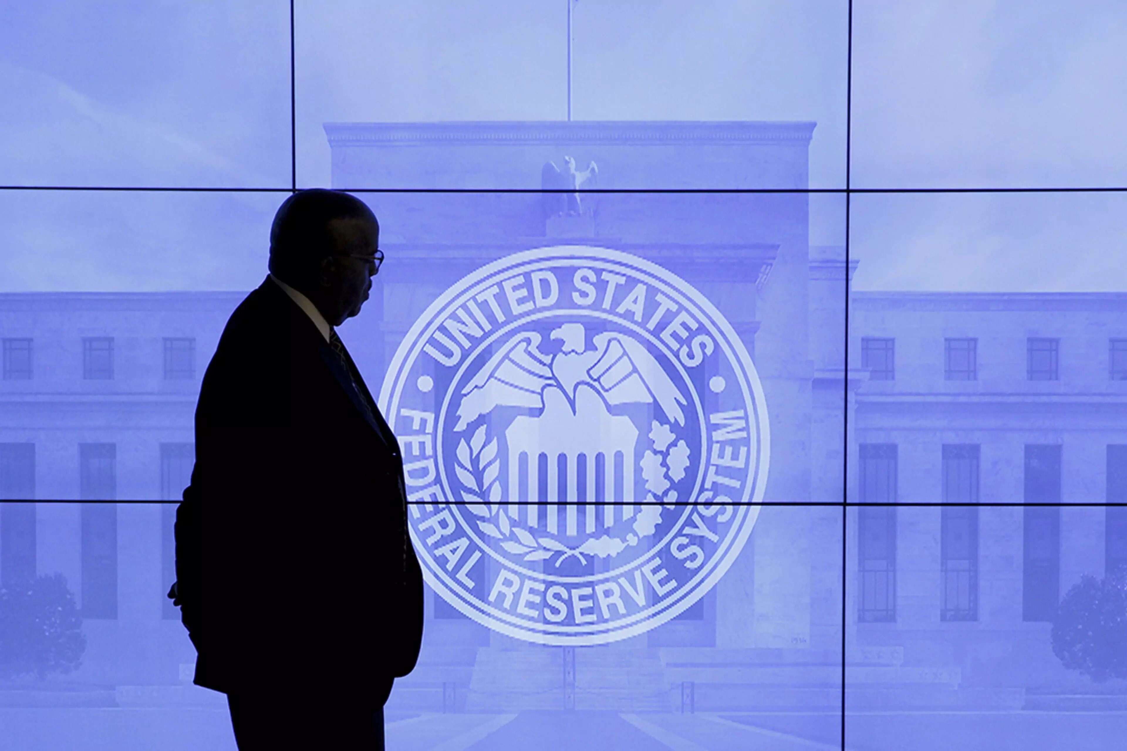 A security guard walks by an image of the Federal Reserve. (Reuters)