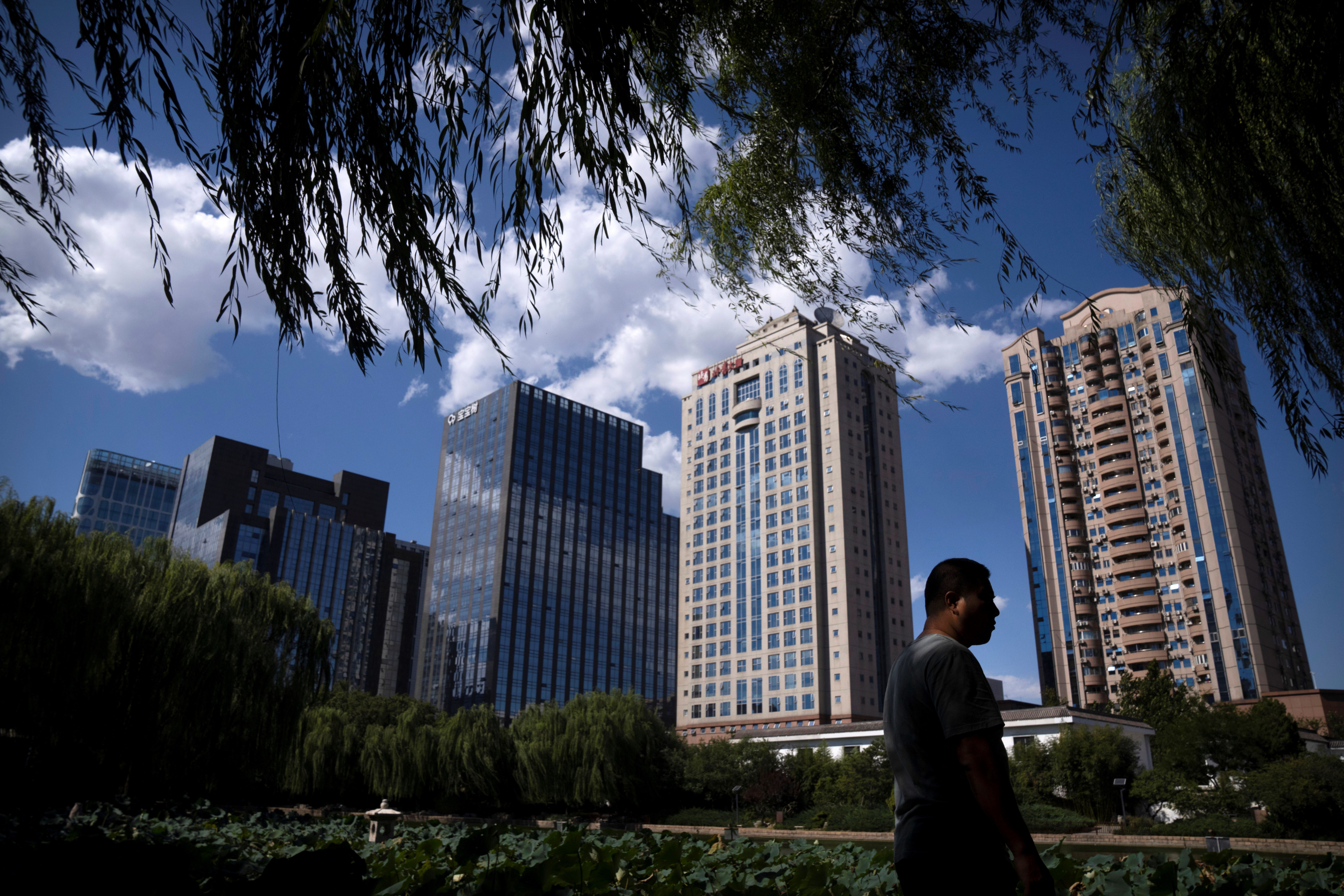 A man walks past a lily pond at a public park on a sunny day in Beijing, Thursday, Sept. 22, 2022 (AP Photo/Mark Schiefelbein)