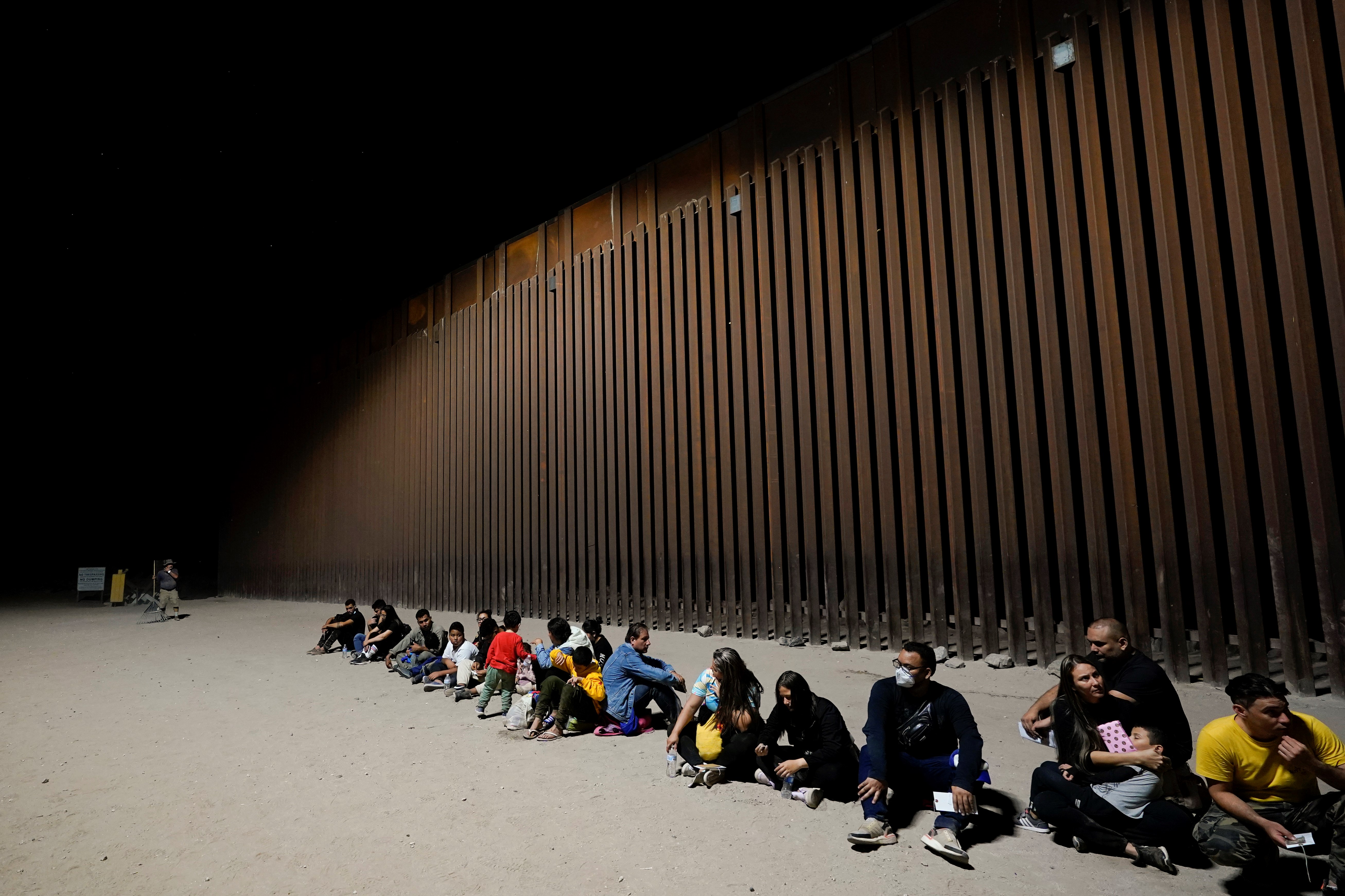 Migrants wait near the end of a border wall Tuesday, Aug. 23, 2022, near Yuma, Ariz (AP Photo/Gregory Bull)