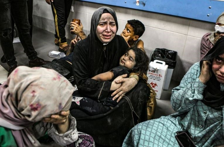 Wounded Palestinian women and children sit on the floor at the Al-Ahli Baptist Hospital following Israeli massacre on Tuesday, October 17. (AP)