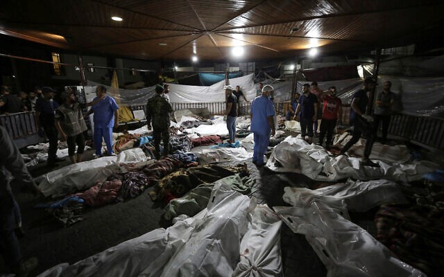 Bodies of Palestinians killed by an explosion near the Ahli Arab hospital are gathered in the front yard of the al-Shifa hospital, in Gaza City, central Gaza Strip, October 17, 2023 (AP)