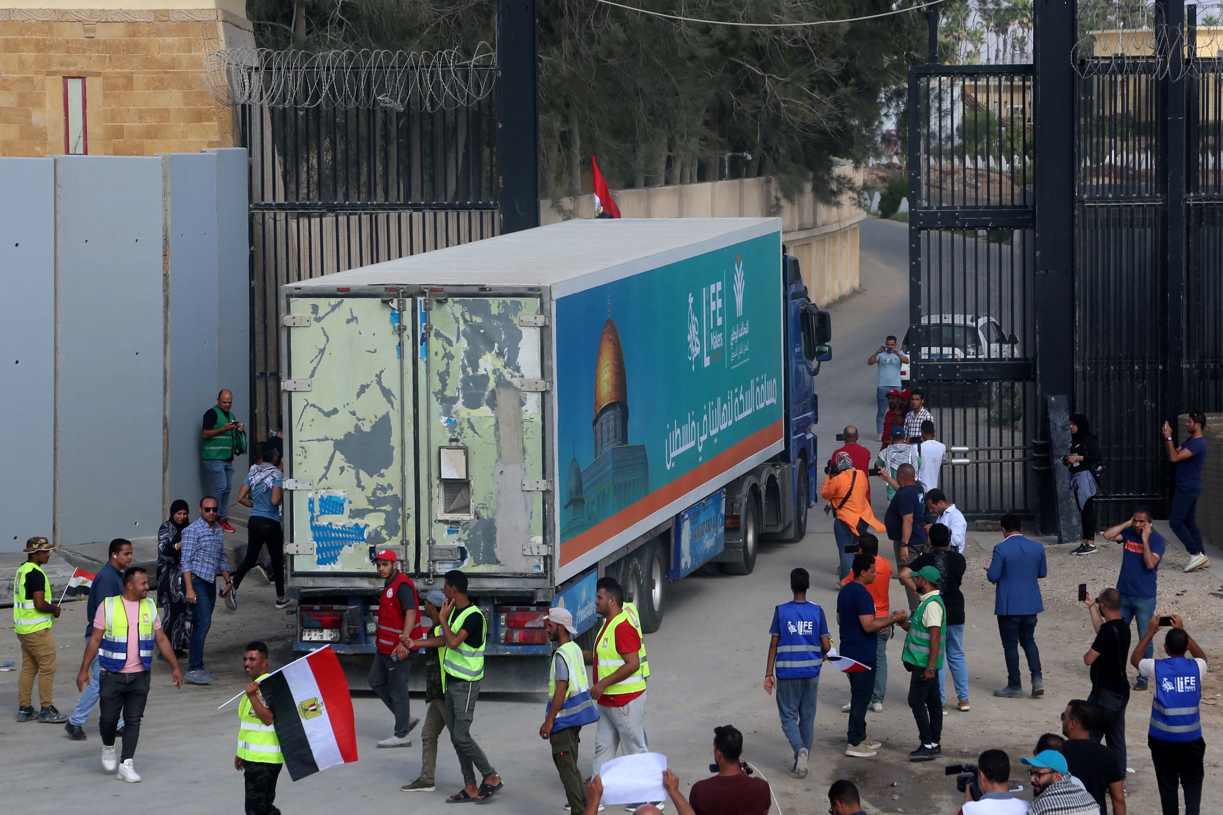 People on the Egyptian side of the Rafah border crossing watch as a convoy of lorries carrying humanitarian aid crosses to the Gaza Strip (AFP)