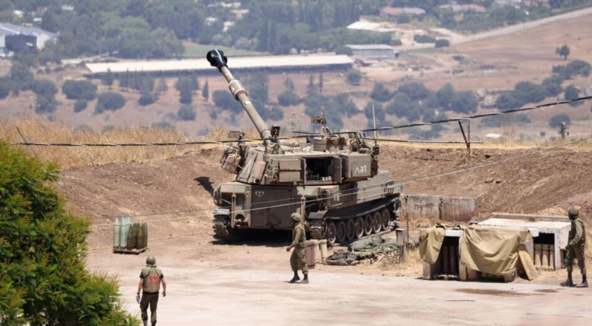 Israeli occupation forces stand near an army self-propelled artillery vehicle on the outskirts of  