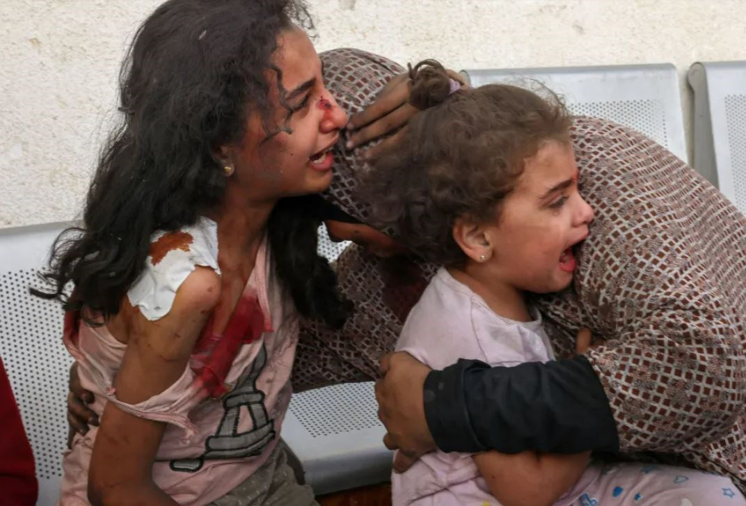 A Palestinian woman comforts her children as they wait at the hospital to be checked due to an Israeli air strike, in the city of Rafah, in the southern Gaza Strip on October 12, 2023. (AFP via Getty Images)