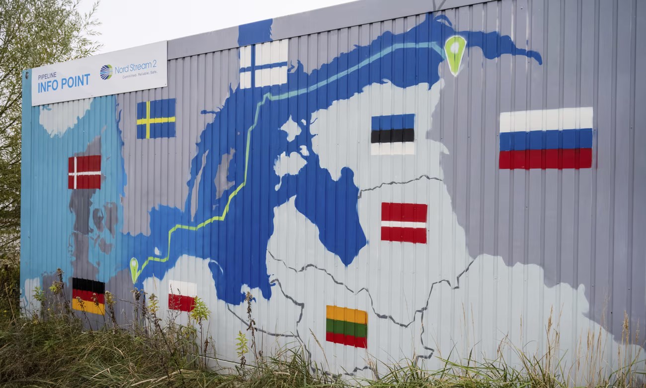 A sign reading ‘Nord Stream 2 Committed. Reliable. Safe’ hangs above a painted map at the natural gas receiving station in the Lubmin industrial estate in Lubmin, Germany (AP)