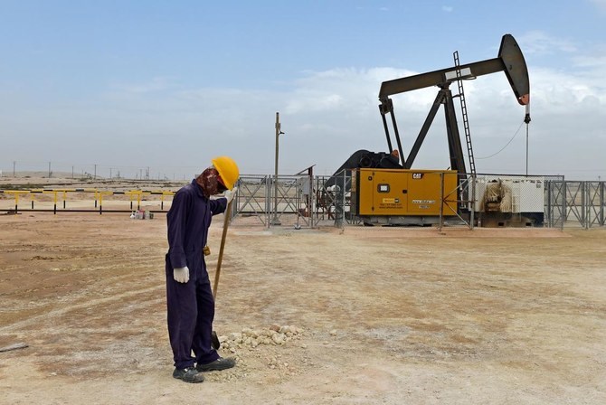 A worker stands across a pumpjack operating in the desert oil fields of Sakhir in southern Bahrain. (AFP)