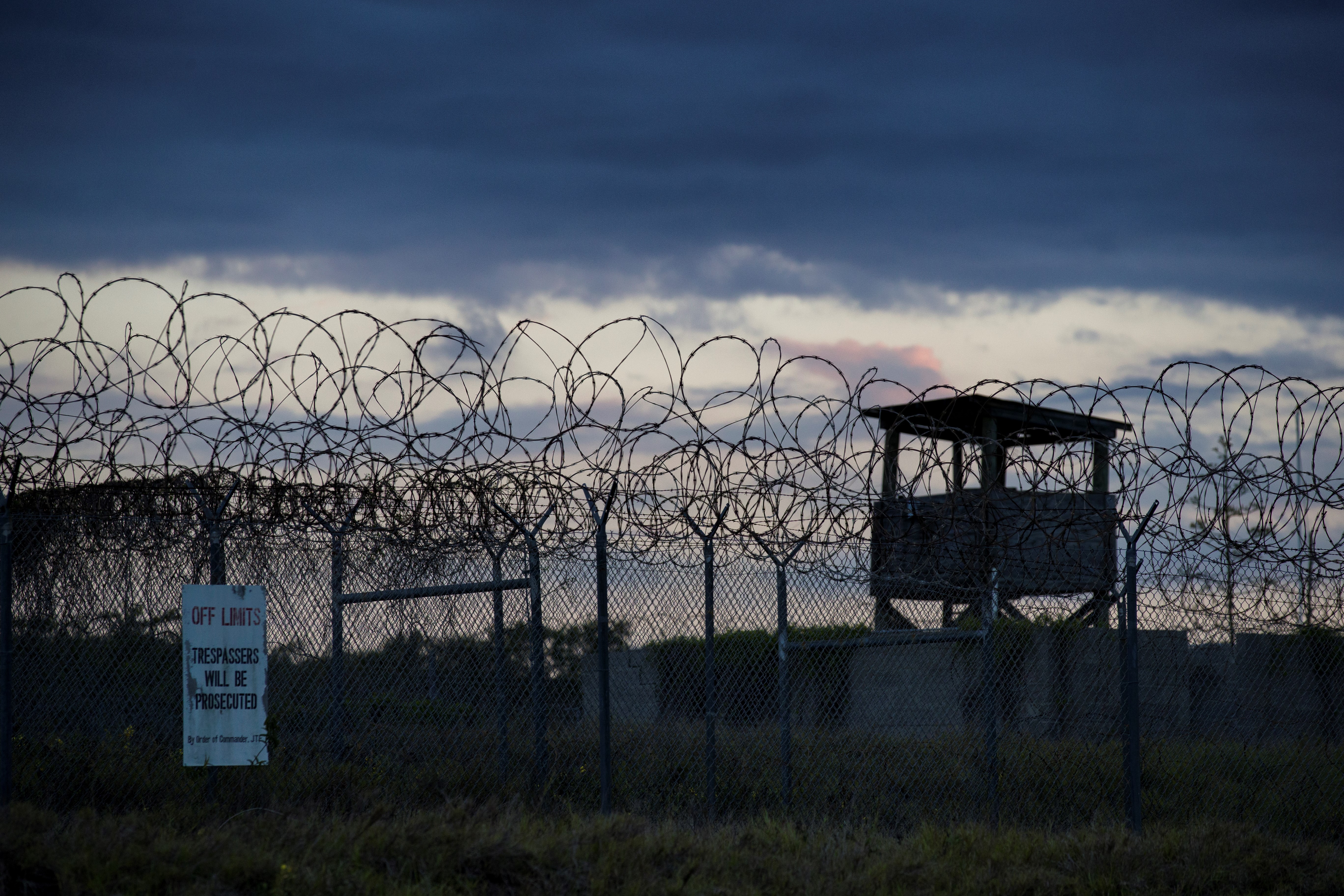 In this photo reviewed by U.S. military officials, the sun sets behind the closed Camp X-Ray detention facility, Wednesday, April 17, 2019, in Guantanamo Bay Naval Base, Cuba (AP Photo/Alex Brandon, File)