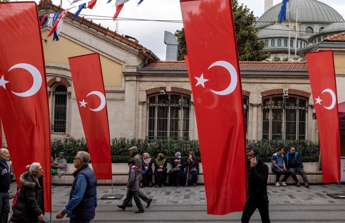 People walk along Istiklal Avenue, decorated with Turkish national flags after Sunday's blast killed six and wounded dozens, in Istanbul, Turkey, November 14, 2022 (Reuters).