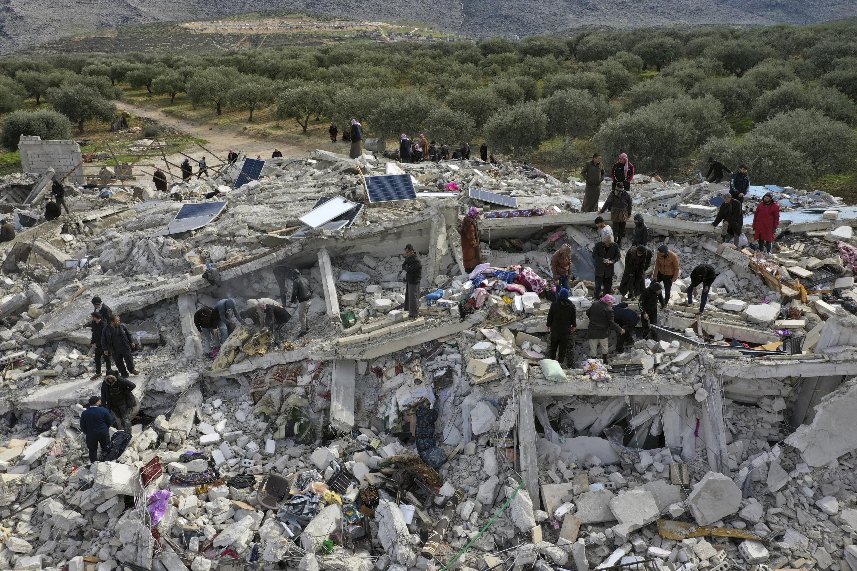 People looking for survivors on a collapsed building in Idlib, Syria on Monday (AP)