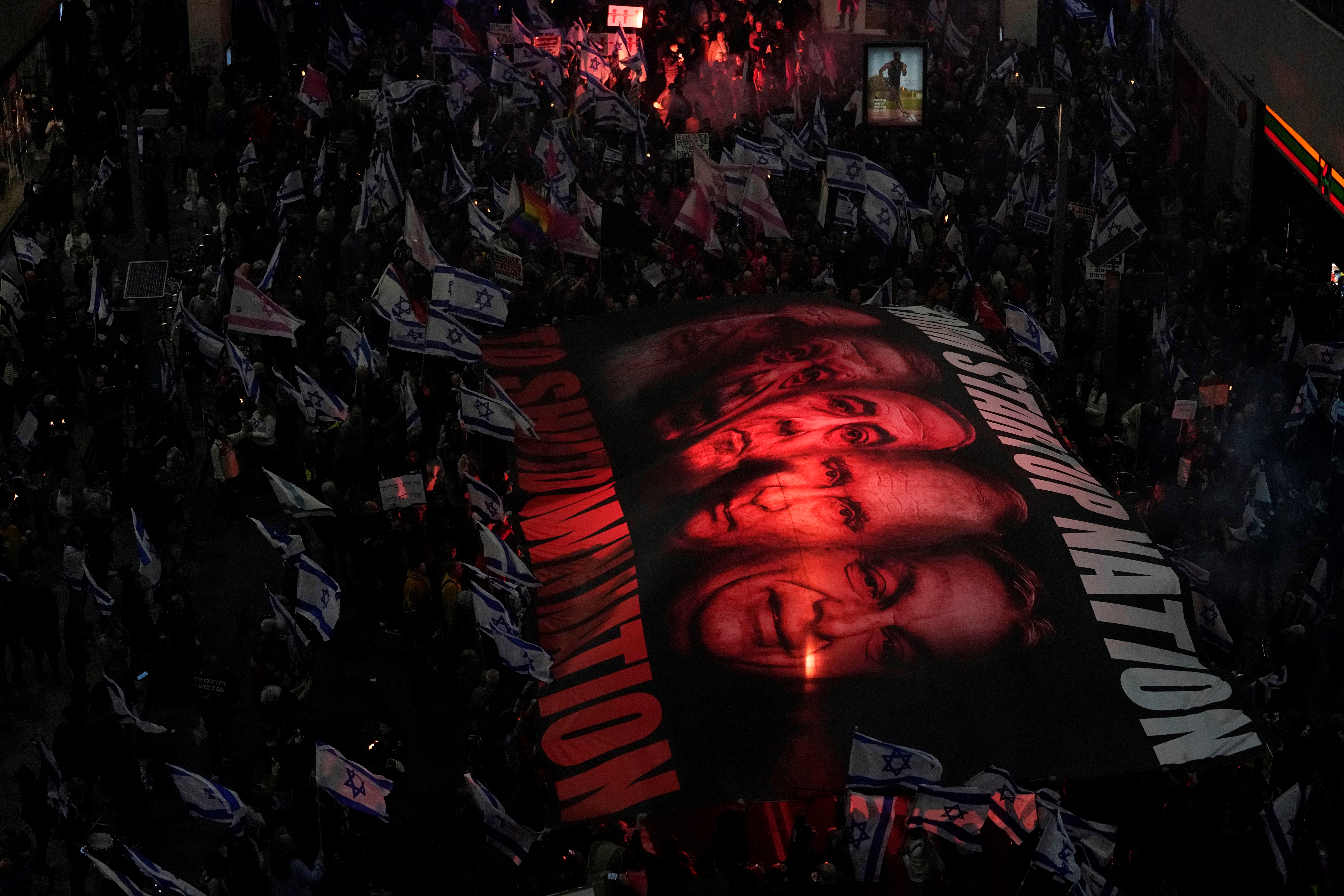 Israelis hold a giant banner depicting Prime Minister Benjamin Netanyahu, center, to protest protest plans by his new government to overhaul the judicial system, in Tel Aviv, Israel, Saturday, Feb. 25, 2023 (AP).