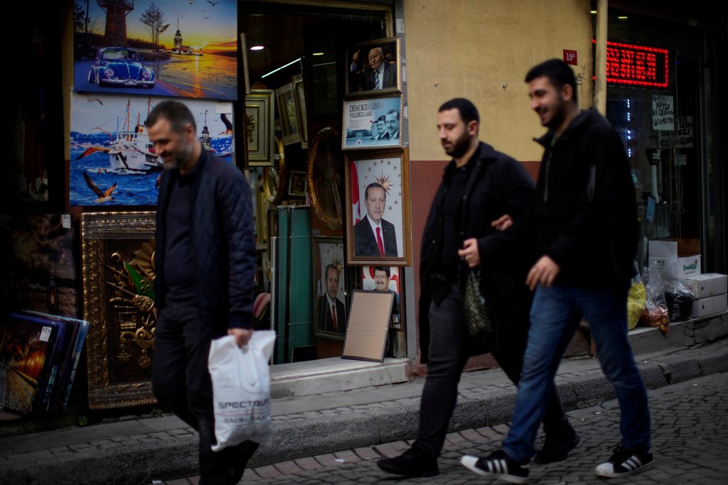 People walk past a photograph of Turkey's President Recep Tayyip Erdogan in Eminonu commercial area in Istanbul, Turkey, Thursday, March 9, 2023 (AP Photo/Francisco Seco)
