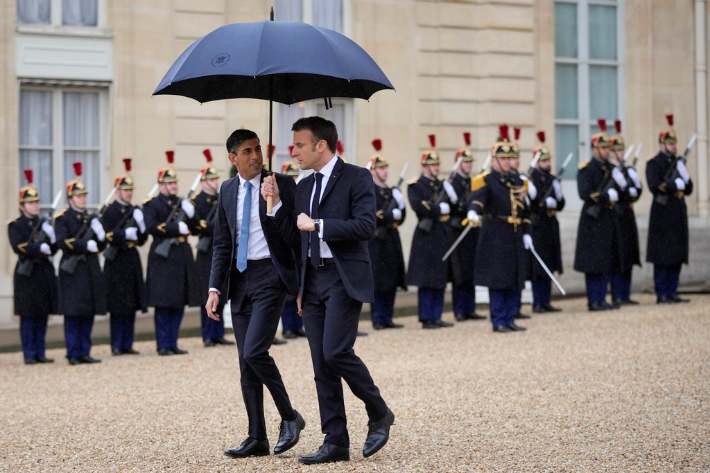 French President Emmanuel Macron, centre right, uses an umbrella to protect Britain's Prime Minister Rishi Sunak after a French-British summit at the Elysee Palace in Paris, Friday, March 10, 2023 (AP Photo/Kin Cheung, Pool)