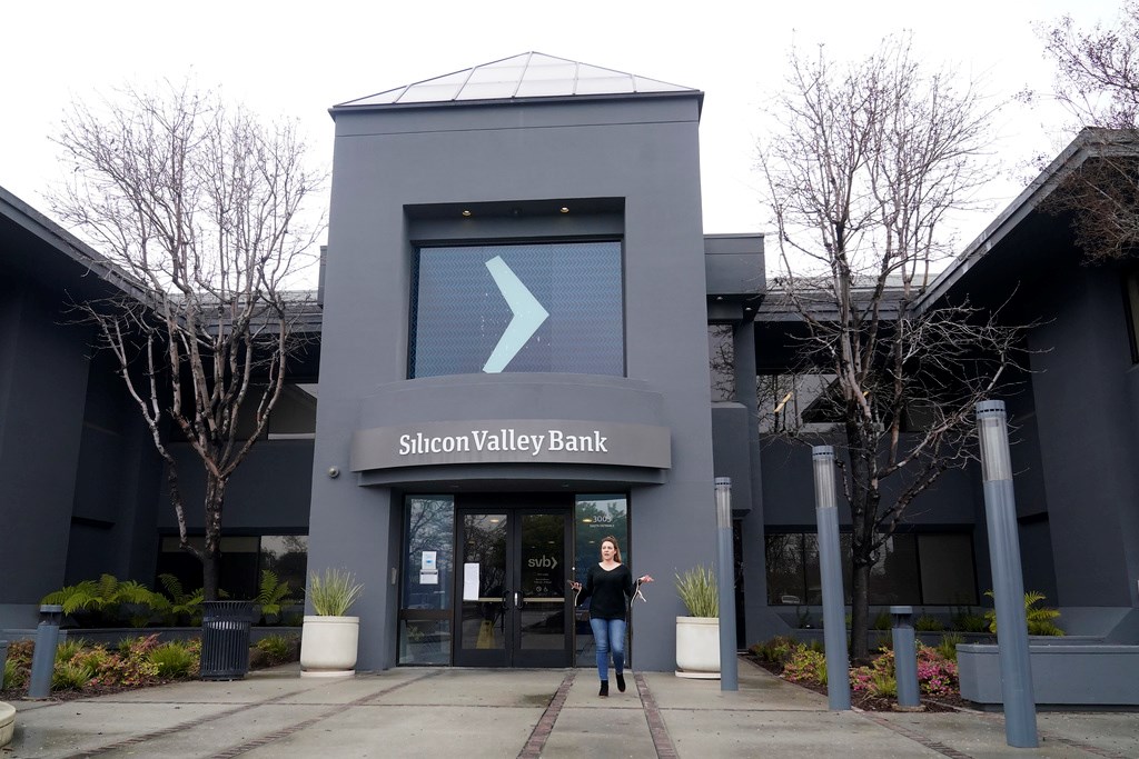 A property managment representative gestures while asking reporters to clear the entrance area to Silicon Valley Bank in Santa Clara, Calif., Friday, March 10, 2023 (AP Photo/Jeff Chiu)