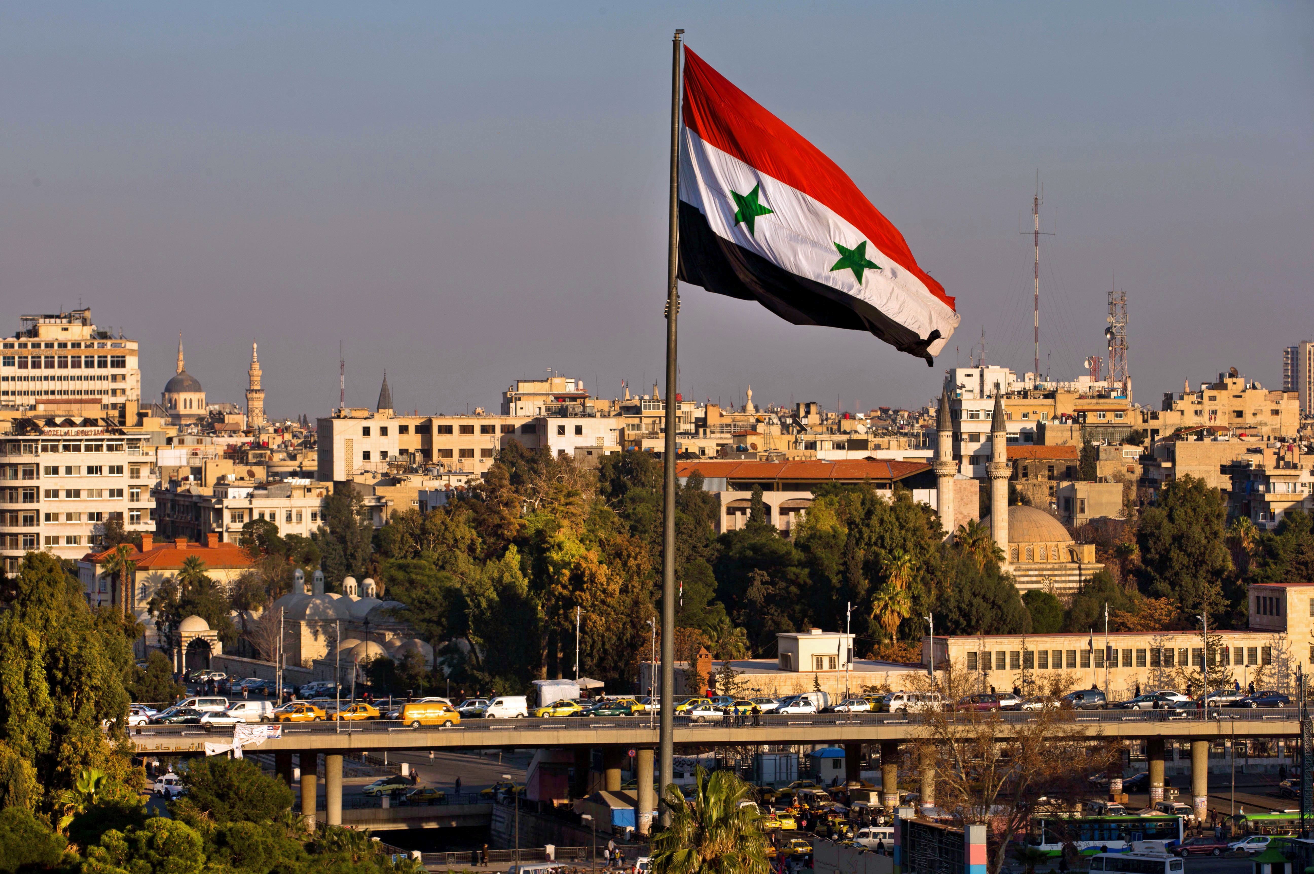 A Syrian national flag waves as vehicles move slowly on a bridge during rush hour, in Damascus, Syria, Sunday, Feb. 28, 2016 (AP Photo/Hassan Ammar)