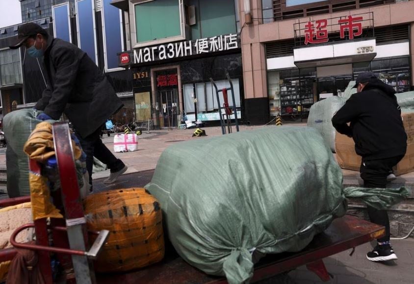 Men move bags of goods for export in front of a trading center that houses shops and offices with Russian goods and services, in Beijing, China April, 1 2022. (REUTERS)