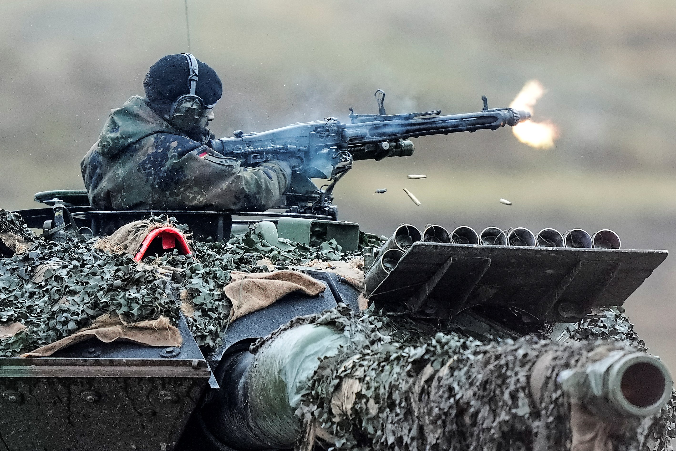 A soldier fires a machine gun from a Leopard 2 tank at the Bundeswehr tank battalion 203 at the Field Marshal Rommel Barracks in Augustdorf, Germany, Wednesday, Feb. 1, 2023 (AP Photo/Martin Meissner)