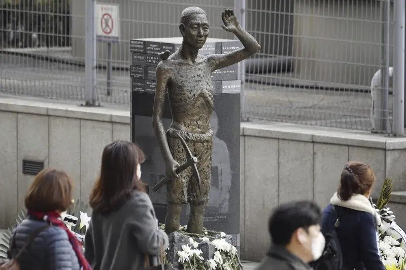 People passing by a statue in Seoul symbolizing forced Korean workers, in March 2023. (AP)