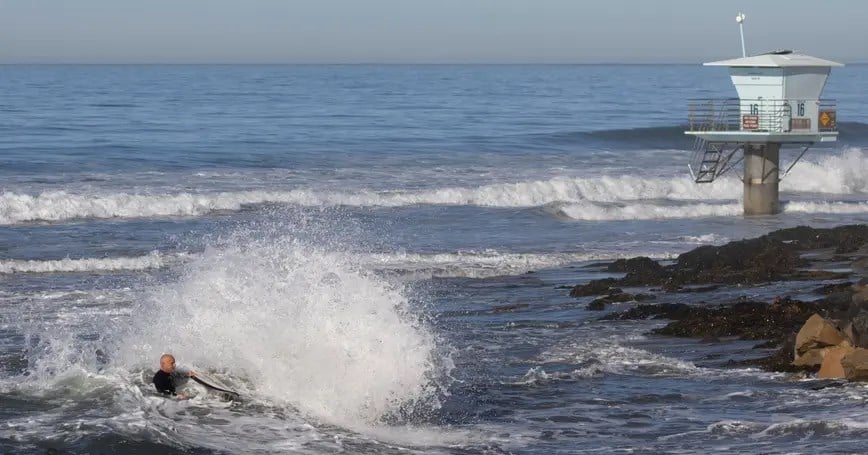 A surfer makes his way to the beach during a King Tide event along the California coastline at Cardiff State Beach. (Reuters)