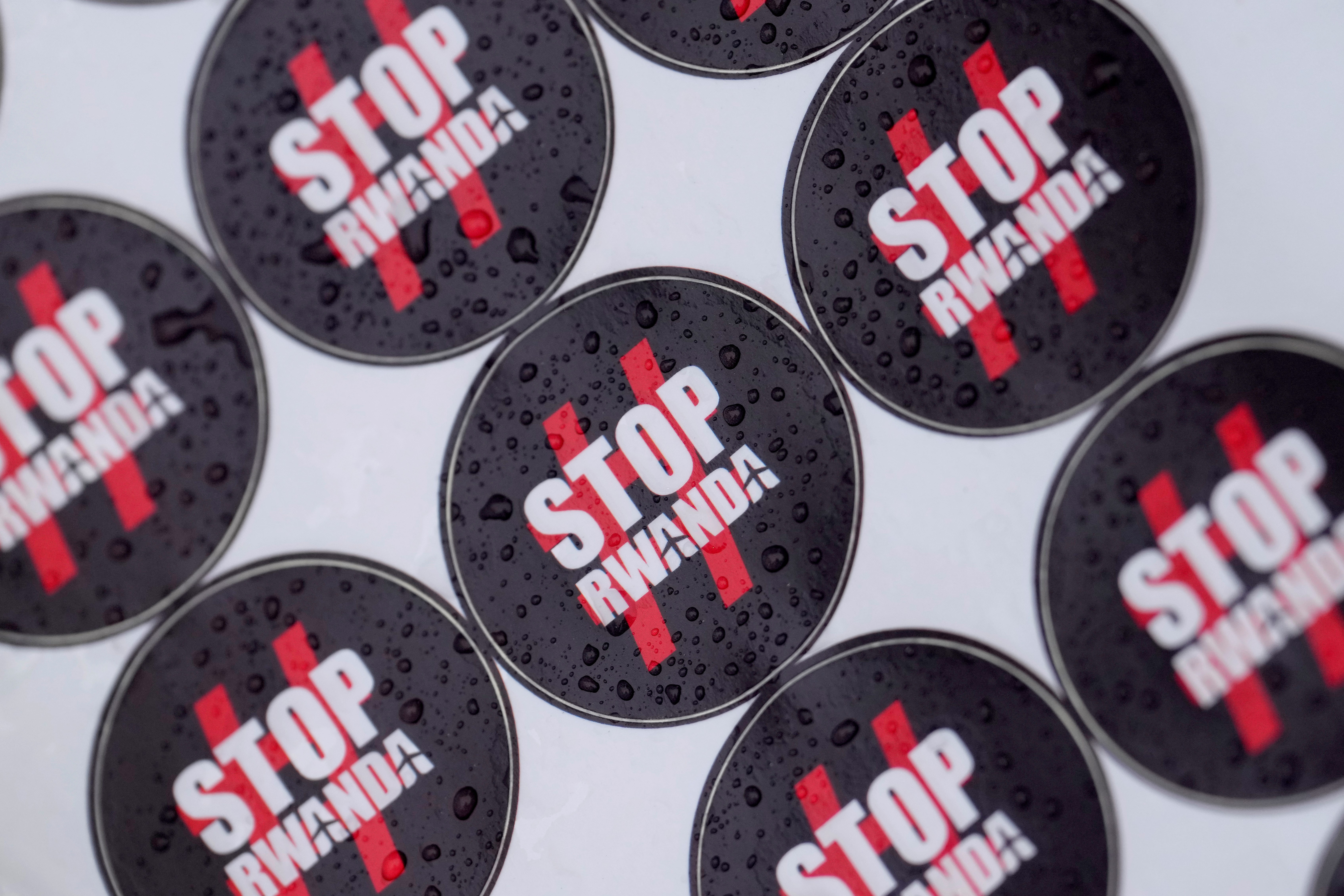 Stickers are covered in rain drops as people protest outside the High Court in London, Monday, Dec. 19, 2022. (AP)