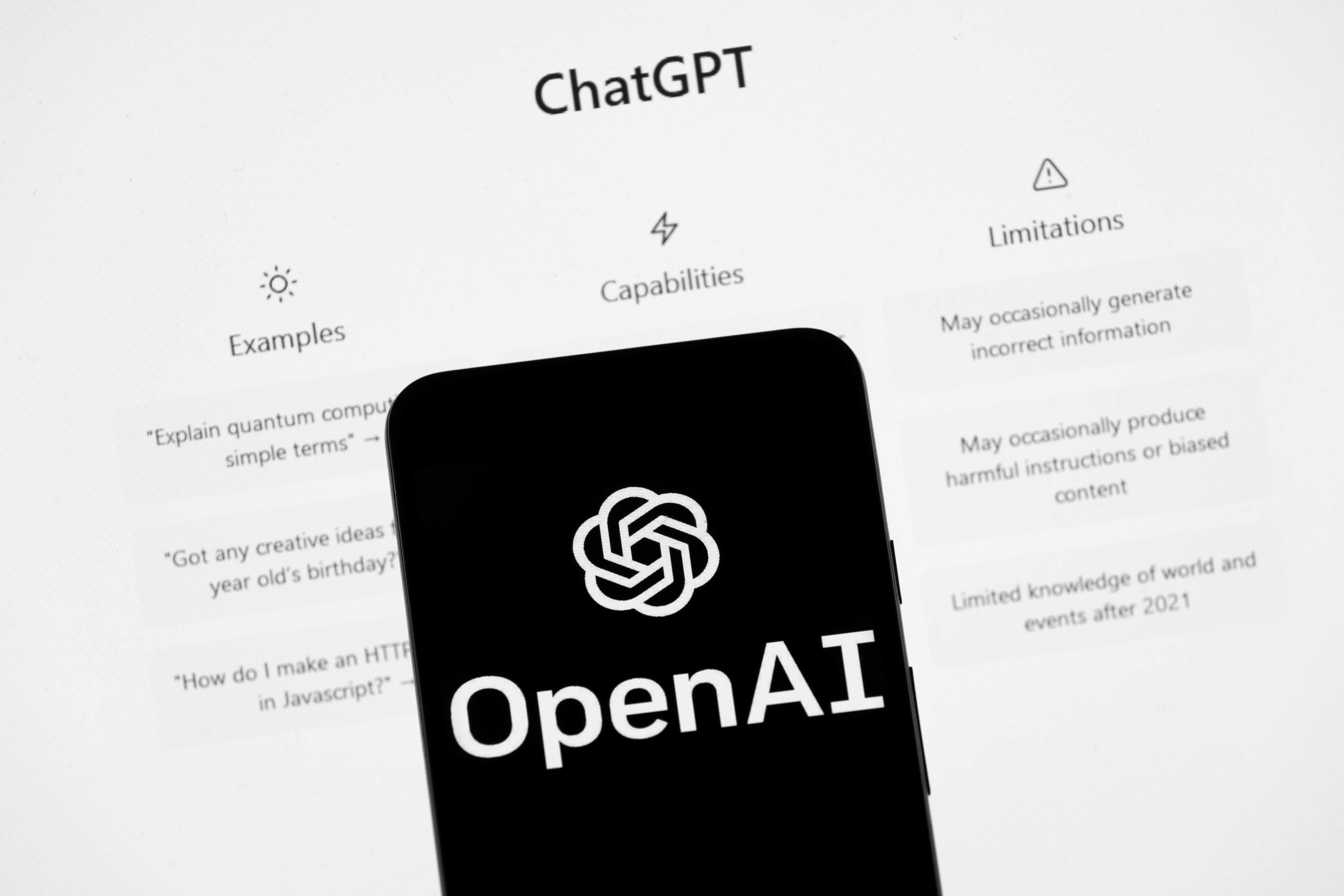 The OpenAI logo is seen on a mobile phone in front of a computer screen which displays the ChatGPT home Screen, Friday, March 17, 2023, in Boston. (AP)