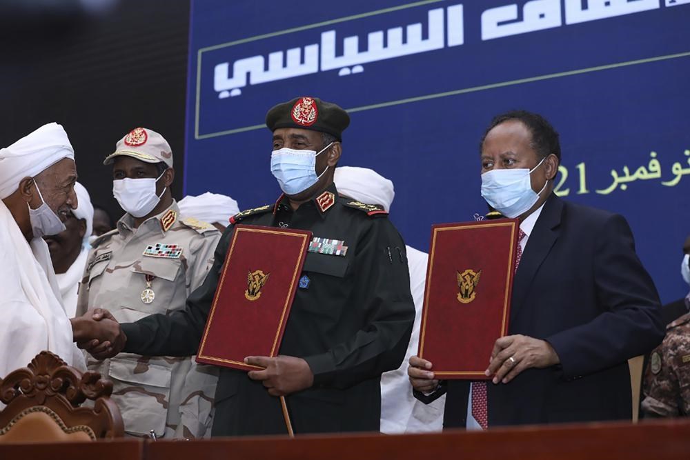 General Abdel Fattah al-Burhan pictured alongside Prime Minister Abdallah Hamdok and Mohamed Hamdan Daglo in a ceremony to reisntate Hamdok who was forced out of office by a coup led by the pair a month before, 25 October 2021. (AP)