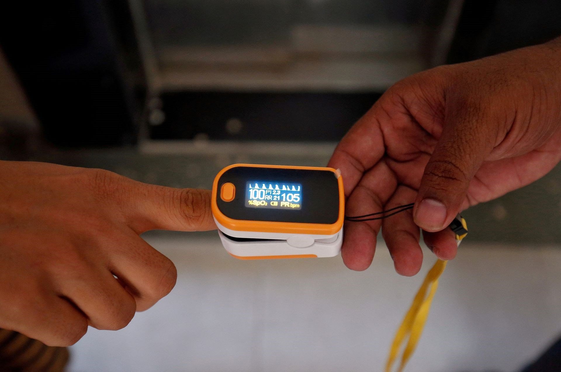 A medical worker (R) puts a pulse oximeter on a woman's finger to check her oxygen level, in India June 26, 2020. (Reuters)