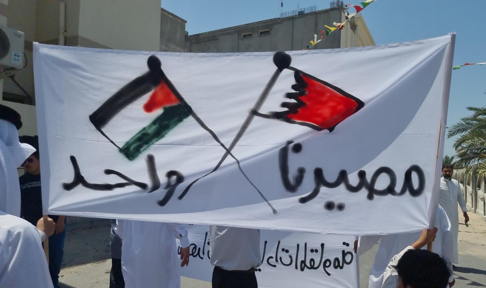 Protesters hold a banner displaying the Palestinian and Bahraini flag which reads out
