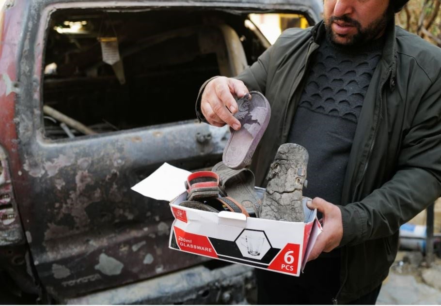 Ajmal Ahmad shows shoes of his nephews, victims of a U.S drone strike that killed 10 civilians, including seven children, as he stands beside a damaged car at the house's courtyard in Khwaja Bughra in Kabul, Afghanistan November 7, 2021. (Reuters)