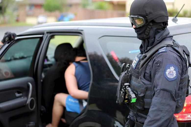 Heavily armed police officers detain a man during early morning raids in western Sydney, Australia, December 10, 2015, in this handout courtesy of New South Wales (NSW) Police (Reuters)