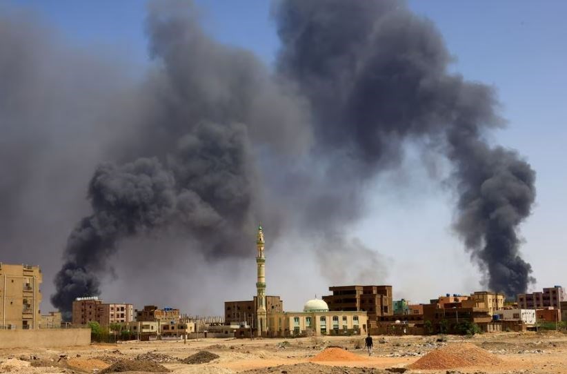 A man walks while smoke rises above buildings after aerial bombardment, during clashes between the paramilitary Rapid Support Forces and the army in Khartoum North, Sudan, May 1, 2023. (Reuters)