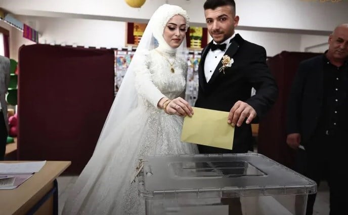 A newlywed couple in a wedding dress and suit cast their votes in the election. (Social media)