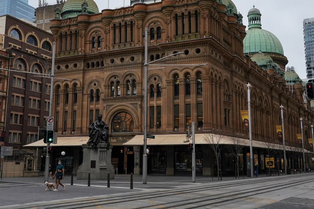 A man walks a dog through the quiet city centre during a lockdown in Sydney, Australia in an undtaed photo (Reuters)