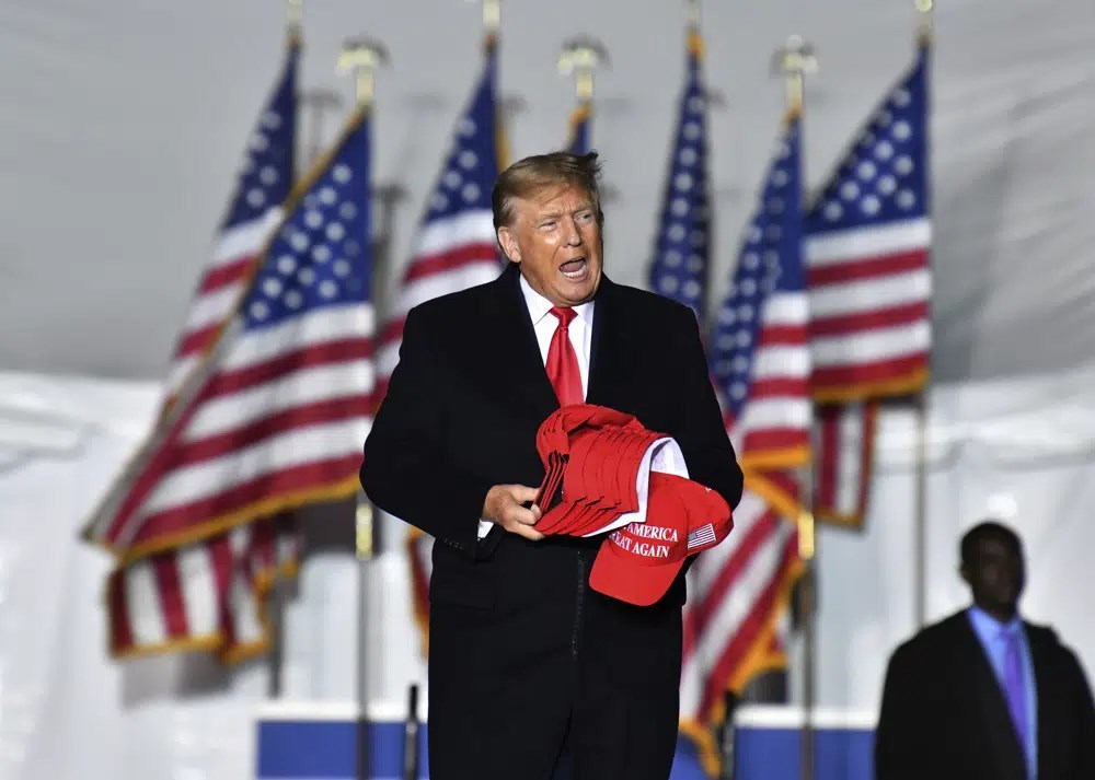 Former US President Donald Trump holds MAGA caps during a rally for Georgia Republican candidates in Columbus, Georgia, US, June 10 2023. (AP)
