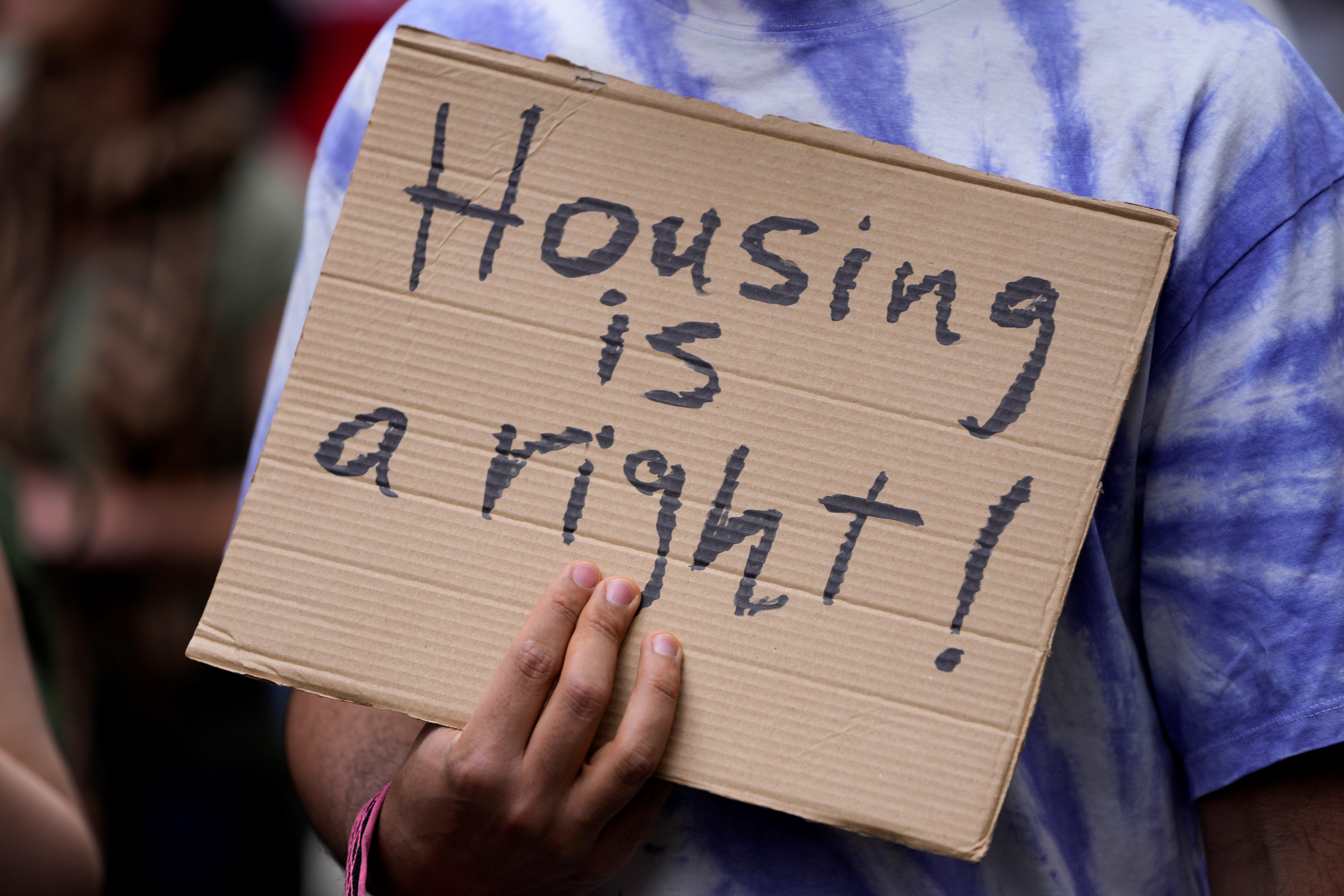 A protestor carries a poster, during a demonstration to demand solutions for Portugal's housing crisis, in Lisbon, Saturday, April 1, 2023. (AP)